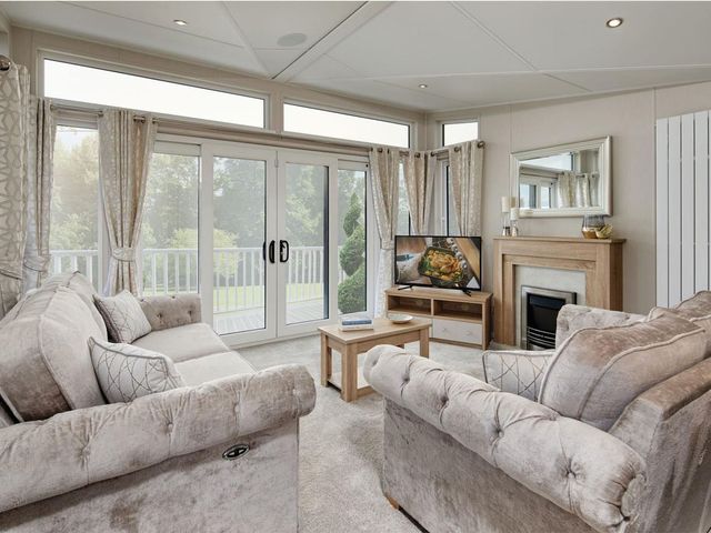 A living room with a sofa and television at 2Br Lodge Pool Fireplace PetsOK Parking in Goonhavern