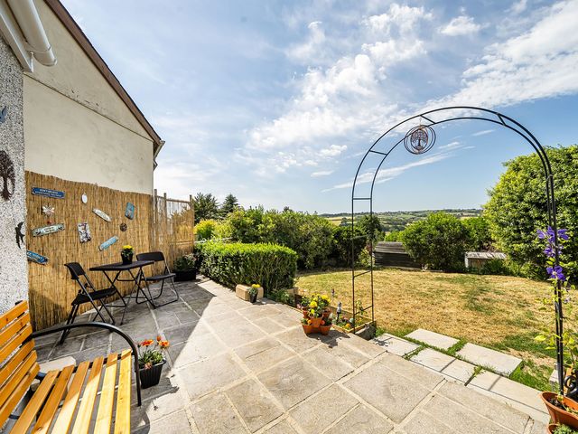A garden with a bench, table and chairs, plants and an archway at Studio Sleeps 2 with Parking and Garden Trewidland near Liskeard
