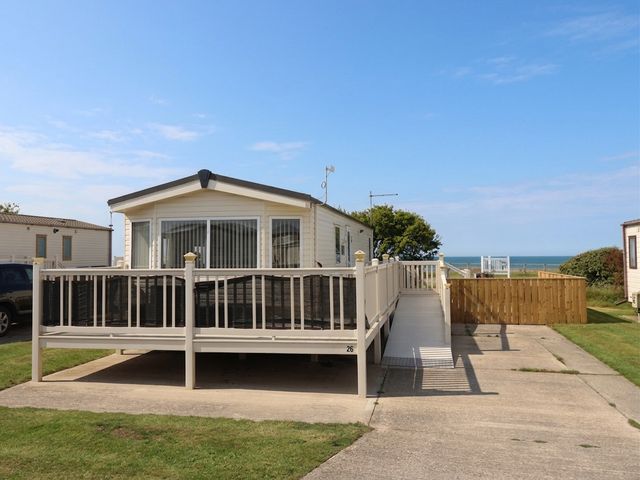 A caravan with decking and a view of the sea at Paws and Relax Driffield