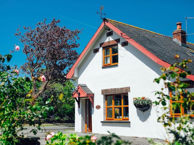 A cottage with a front door and flower garden at Barn Cottage in Haverfordwest