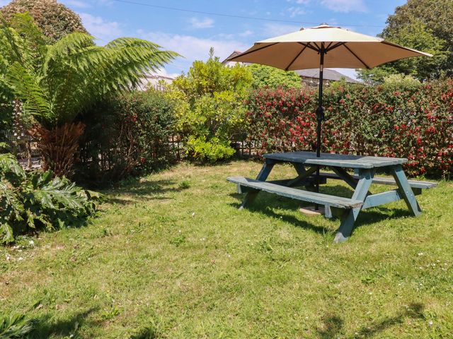 A picnic table with an umbrella in a garden at The Jingle House in Tregony