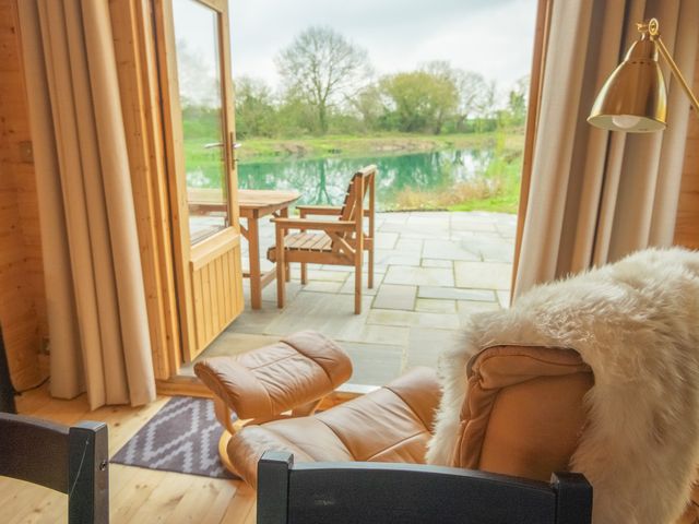 A living room with a view of a lake at Willow Lodge in Stowmarket