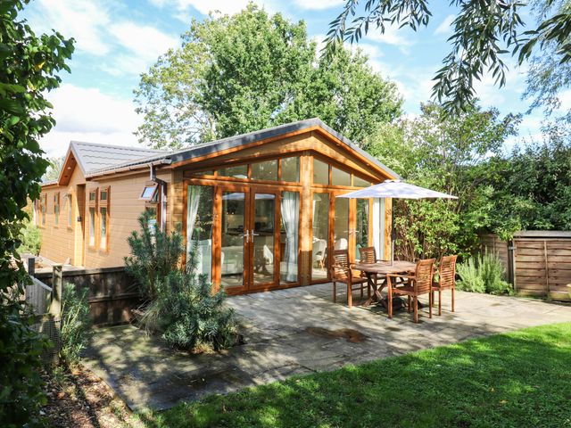 A wooden lodge with outdoor patio and dining set at Willow Lodge Stowmarket