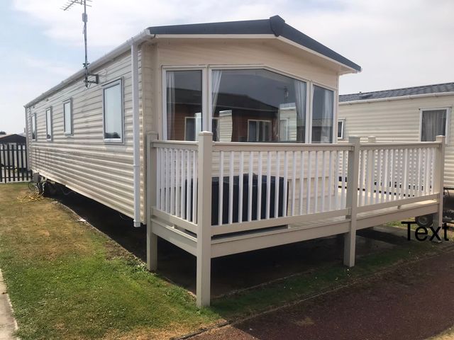 A caravan with a deck and railing at Golden Sands FSB38 in Rhyl
