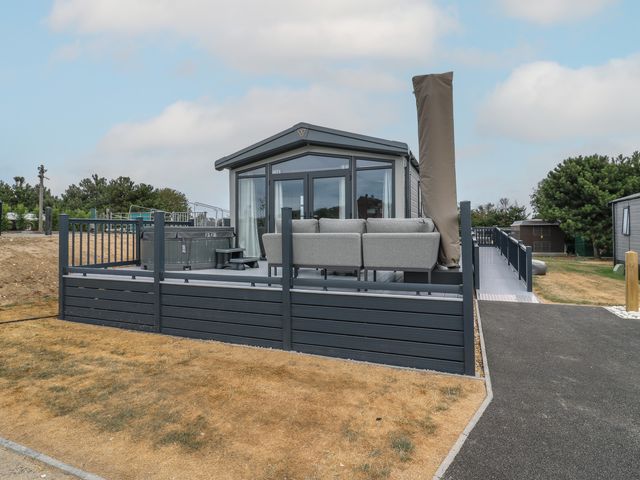 An outdoor area with a hot tub and grey sofa at Lodge 1 St. Osyth