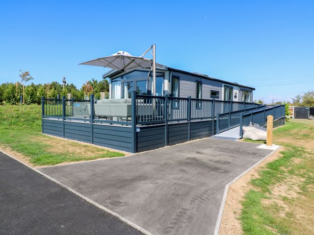 An outdoor seating area with a parasol and decking at Lakewood Plot 1 in St. Osyth