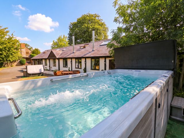 A hot tub and house in the outdoor area at The Warm Hearth in Hereford