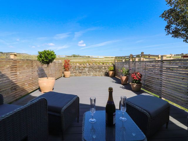 An outdoor area with a deck, chairs, and a table at The Swallows near Glasson