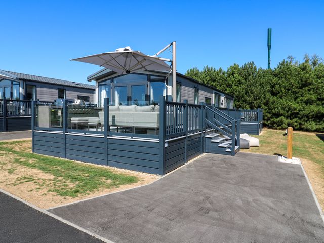 A deck with a couch and umbrella at Lakewood Plot 3 St. Osyth