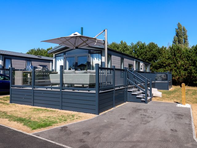 An outdoor area with a sofa and umbrella at Lakewood Plot 5 St. Osyth