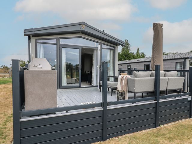 An outdoor area with a sofa and barbecue at Lodge 2 St. Osyth