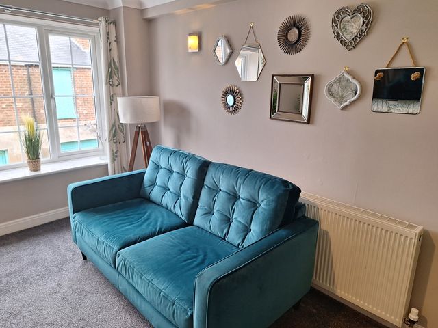 A living room with a sofa and decorative mirrors at Old Coach House Apartment in Scarborough