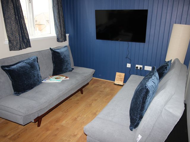 A living room with sofas and a television at Cornerhouse Apartment 4 Llandudno
