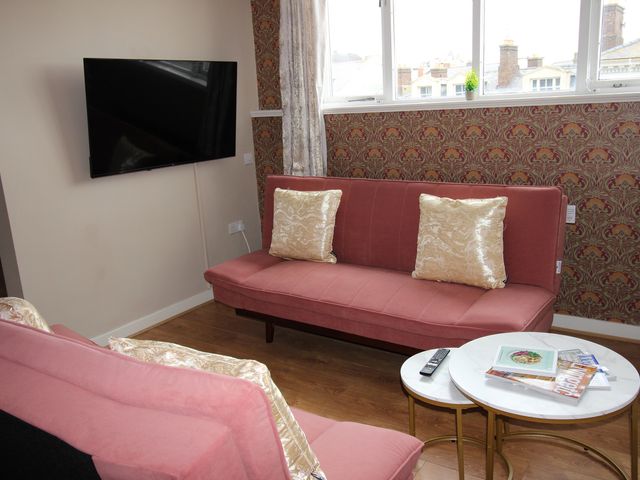 A living room with a television and sofa at Cornerhouse Apartment 5 in Llandudno