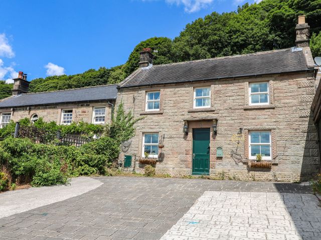 A cottage with stone walls and a green door at Jasmine Cottage Matlock