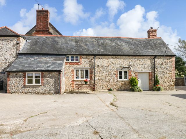 A cottage with a bench and flower pot at The Cheese House near Charmouth
