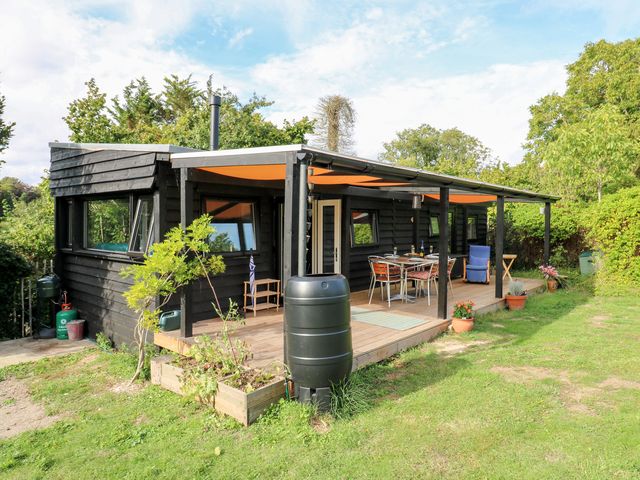 A cabin with a deck, table, and chairs at Orchard Lodge in Dover