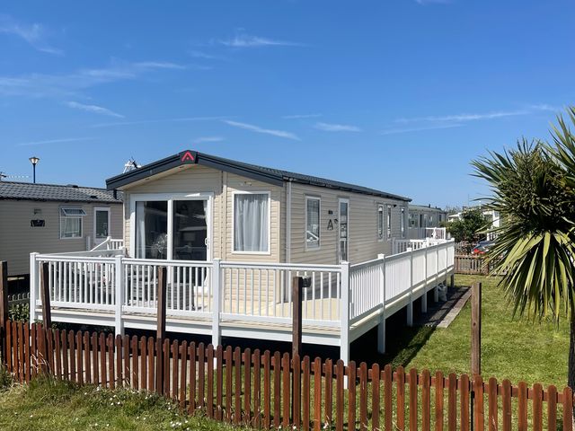 A mobile home with a deck and a fence at Unity Beach in Burnham-on-Sea