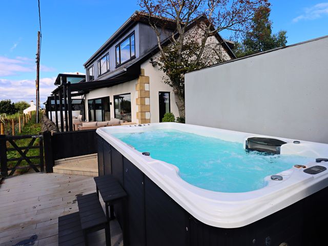 A hot tub with deck and house in the background at Parrott's Nest in Hyde