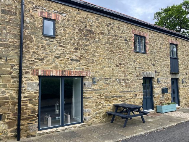 An outdoor area with a stone wall and a picnic table at The Old Dairy near Liskeard