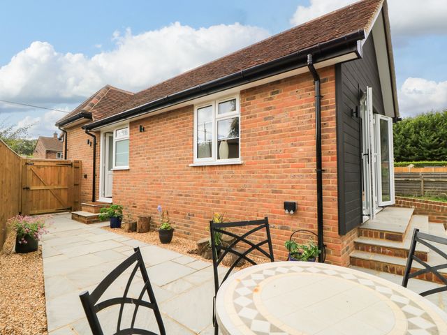 An outdoor area with a house, patio, and seating at Kingswick Lodge in Naphill