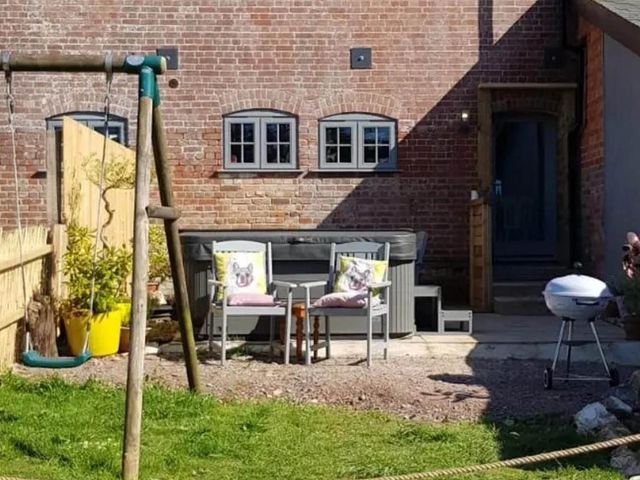 A garden with a swing, chairs, hot tub, and grill at 3 Bedroom Cottage Hot Tub Garden Parking Dunkeswell
