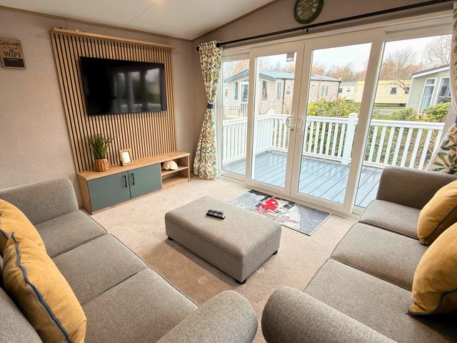 A living room with a television and sliding doors at Vintage 121 Southview Holiday Park Skegness