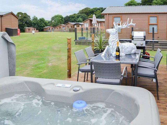 An outdoor area with a hot tub and dining table at Boutique lodge with hot tub sleeps 6 in Bridlington