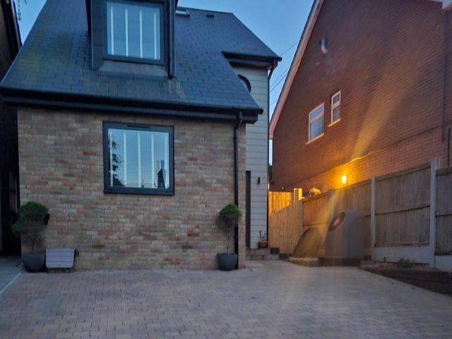 An outdoor area with a brick wall, windows, and a driveway at 5 Bed Sleeps 7 New Build Detached Property in Monkton near Minster