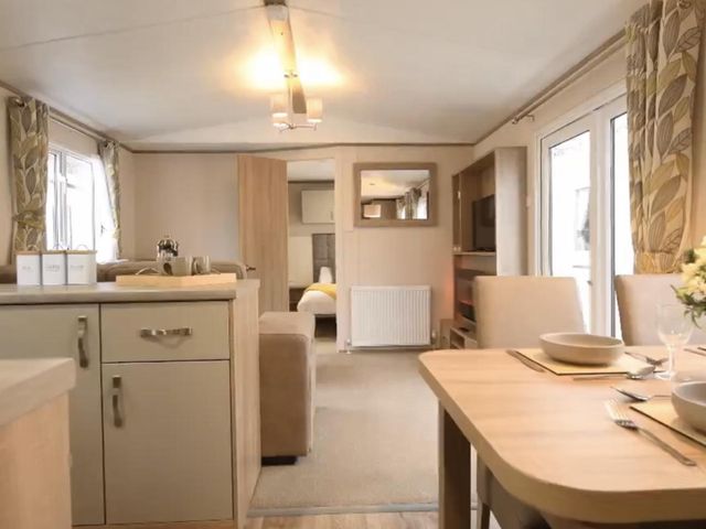 A living room with a dining table and kitchen island at a holiday home