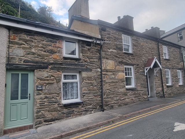 A stone house with a door and windows at Ty Kate in an outdoor setting