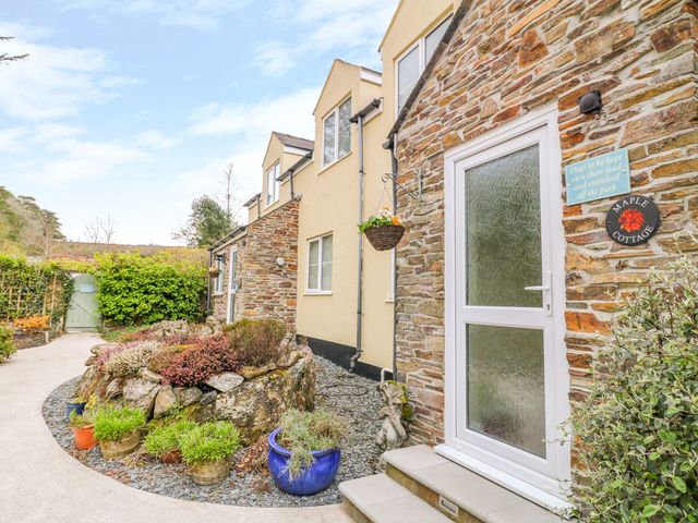 A garden entrance with a stone wall and potted plants at Maple Cottage in Tavistock
