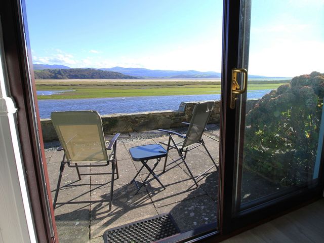 An outdoor seating area with chairs and a table overlooking the water at Aldena South Snowdon Wharf Porthmadog