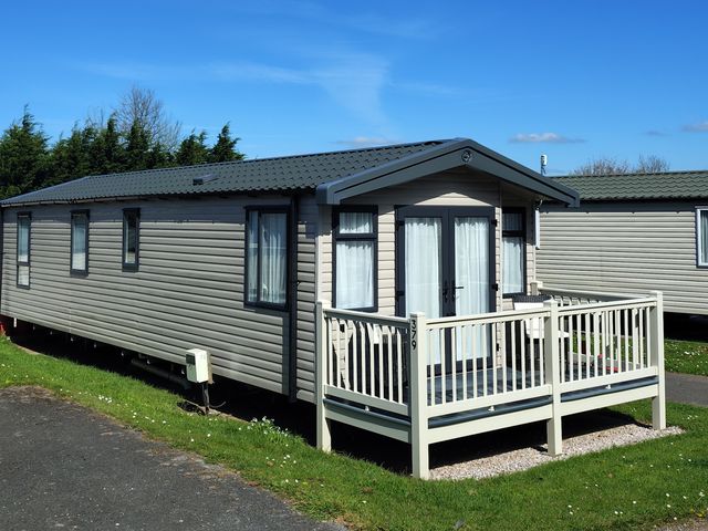 A caravan with a deck in front at Beverley Bay Paignton