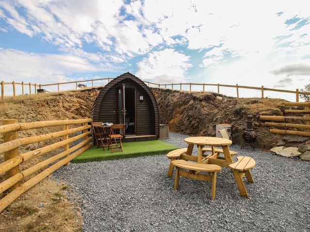 An outdoor seating area with a camping pod and wooden furniture at Darn Mawr in 
