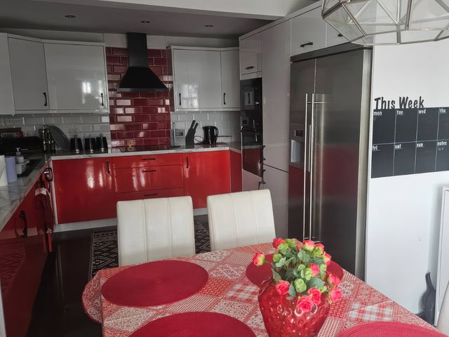 A kitchen with red cabinets and appliances at Mourne Mountains View in Dunmurry