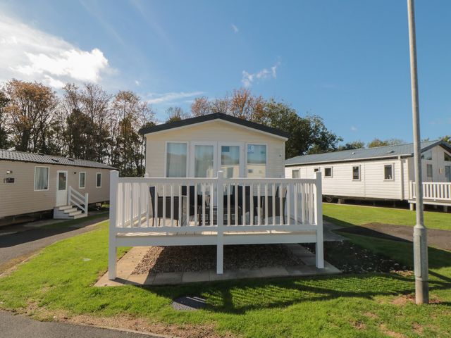 A mobile home with a deck and railing at 14 Pines in Cayton Bay