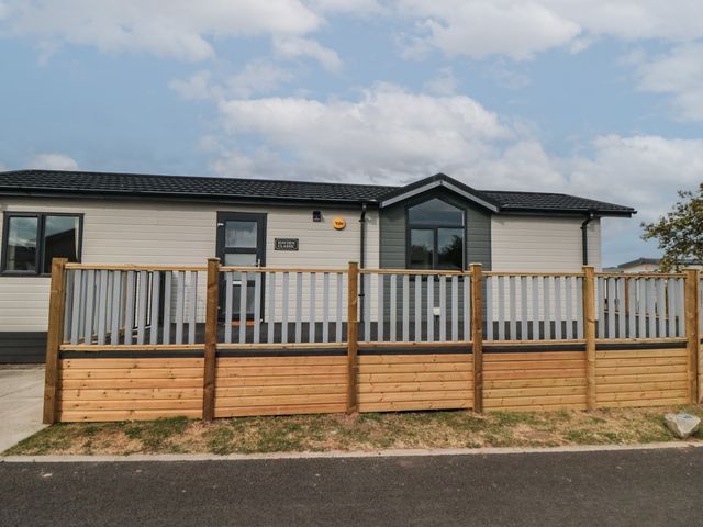A mobile home with a wooden deck and fence at Sea Glass Lodge in Saltburn-by-the-Sea