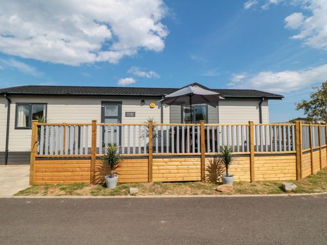 A house with decking and an umbrella at Sea Glass Lodge in Runswick Bay