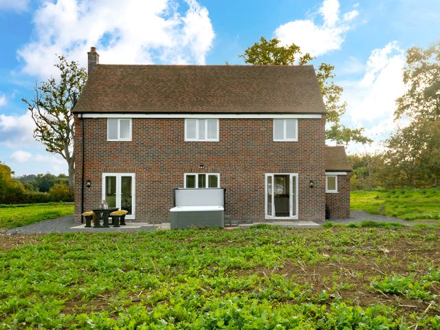 A house with a table and hot tub in the yard at Hambledon Hill Cottage in Blandford Forum