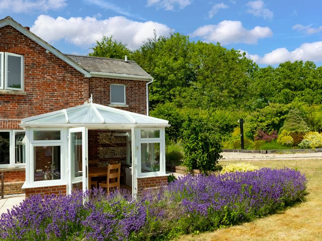 A conservatory with a dining table and chairs at Charming Countryside Cottage in Blandford Forum