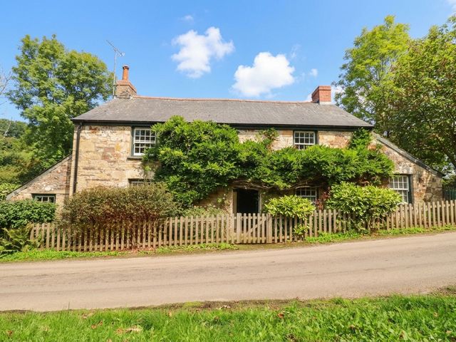 A stone house with a fence and trees at The Homestead in 