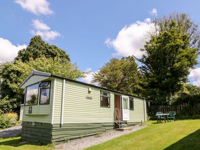 A mobile home with chairs on grass at Brent Tor in Tavistock