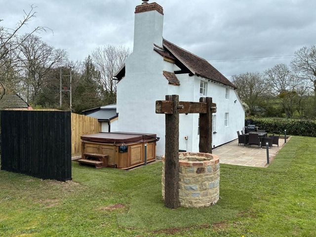 A garden with a hot tub, well, and seating area at a property