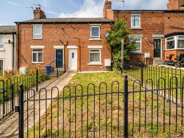 A brick house with a garden and fence at the property
