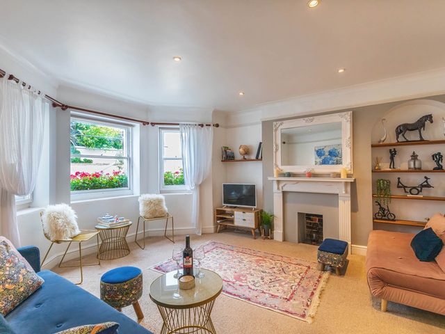A living room with a sofa, coffee table, and television at Seafront Apartment Private Garden Free Parking in Littlehampton