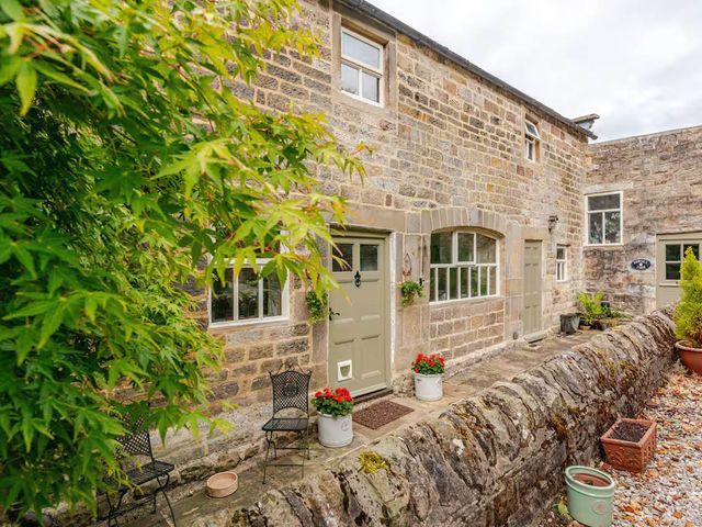 An outdoor view of a stone building with chairs and plants at Dowgill 3Bed Barn Sleeps 7 Hot Tub Parking Near Summerbridge