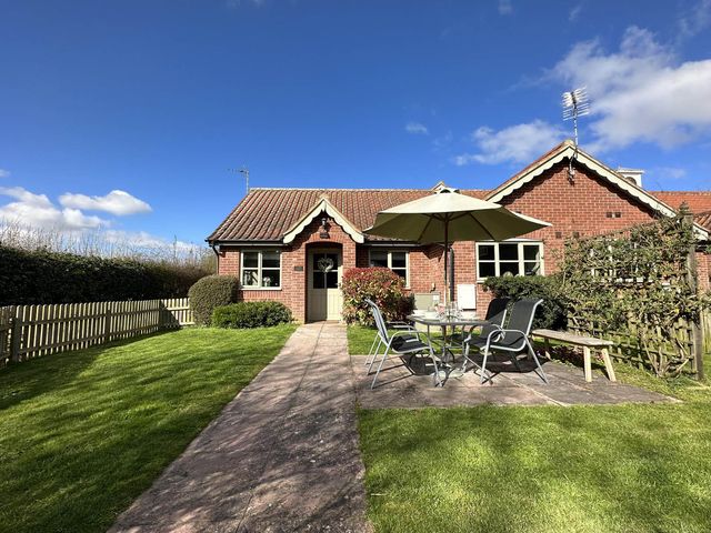 A garden with a table, chairs, and umbrella at Cottage Sleep 4 Pet Friendly Enclosed Garden, Rollesby, near Scratby