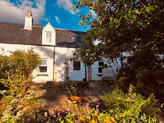 A house with a garden and flowers outside Cosy Cottage Retreat in Edinbane near Portree