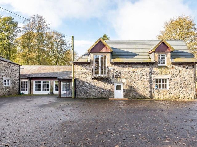 An outdoor view of a stone building with multiple windows and a driveway at Luxury Duplex Sleeps 2 Hot Tub Balcony Parking Duncrievie near Milnathort